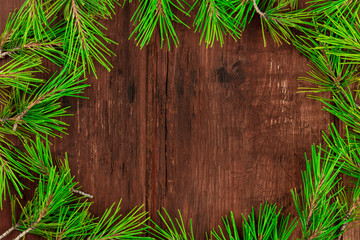 A Christmas composition with fir tree branches on a dark wooden background with copy space, shot from the top