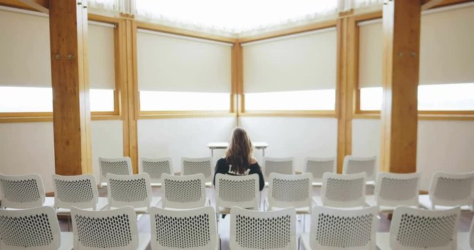 Back view of woman sitting in empty meeting room