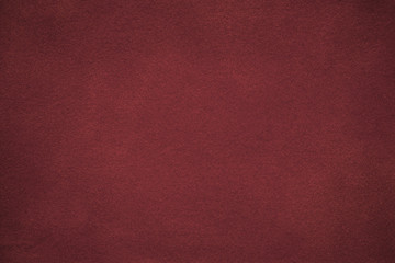 Background of dark red suede fabric closeup. Velvet matt texture of wine nubuck textile with...