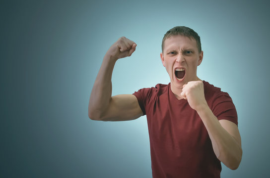 Angry Man In Stress Is Shouting And Is Shaking By His Fist Isolated On Blue Background.