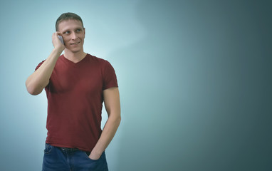 Young man is talking by mobile phone in his hands and looking up isolated on blue background with copy space.