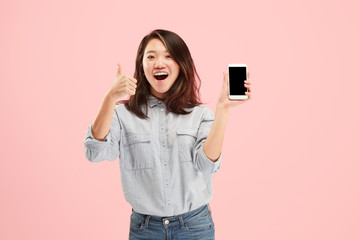 Fototapeta premium Portrait of a confident casual girl showing blank screen mobile phone isolated over pink background.