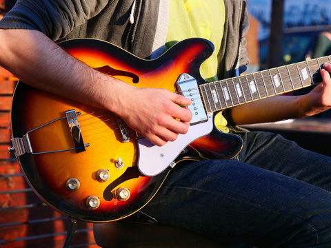 Male hands play an electric guitar on the street