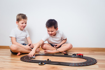 preschool children in white t-shirts run cars on the track