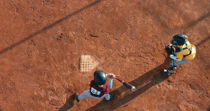 OVERHEAD CRANE Kid boy batter baseball player hits a ball over a home plate. 4K UHD 60 FPS SLO MO RAW