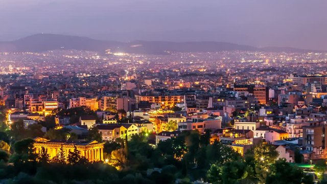 Panoramic view of Athens with Temple of Hephaestus. City skyline at dusk. Day to night time lapse video. City lights switch on.