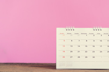 close up of calendar on the table with pink background, planning for business meeting or travel planning concept - obrazy, fototapety, plakaty