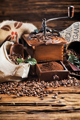 Bag of roasted coffee beans with old wooden mill