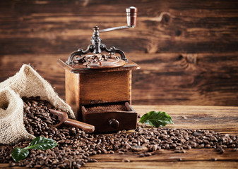 Rustic coffee mill with beans spilling from a bag