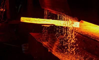 Hot iron in smeltery held by a worker. Melting of metal in a steel plant. High temperature in the...