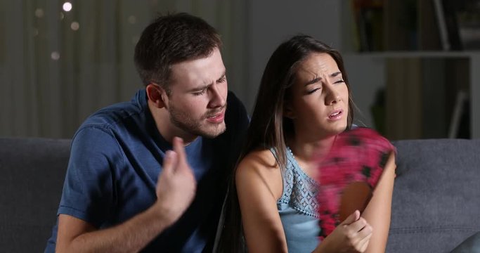 Couple suffering a heat stroke sitting on a couch in tle living room at home in the night