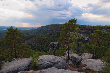 Fototapeta na wymiar Scenic panorama with typical rocky peaks, ancient forest under cloudy sky. Bohemian Switzerland National Park. Famous touristic place and travel destination in Europe. Czech Republic
