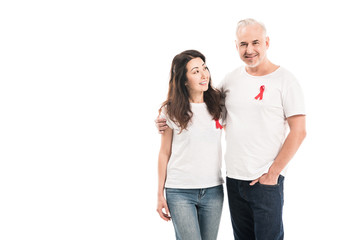 smiling adult interracial couple in blank t-shirts with aids awareness red ribbons embracing isolated on white