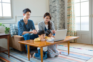 リビングでパソコンを囲む家族4人