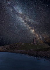 Fototapeta na wymiar Vibrant Milky Way composite image over landscape of Dunstanburgh Castle on Northumberland coastline in England