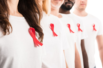 cropped shot of group of people in blank white t-shirts standing in row with aids awareness red ribbons isolated on white