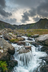 Fototapeta na wymiar Moody landscape image of river flowing down mountain range near Llyn Ogwen and Llyn Idwal in Snowdonia in Autumn