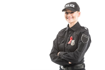 happy female police officer with aids awareness red ribbon looking at camera with crossed arms isolated on white