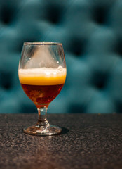 Close up on a glass of amber Pale Ale beer on wooden table in bar with copy space.