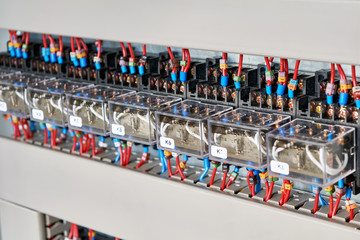 A range of electrical intermediate relays in an electrical Cabinet. The wires are connected to the...