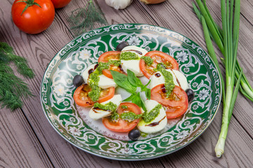 Fresh italian caprese salad with mozzarella and tomatoes on dark plate