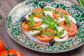 Fresh italian caprese salad with mozzarella and tomatoes on dark plate