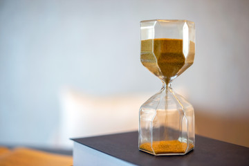 Hourglass and old book with blurred background. Leave copy space for adding text.