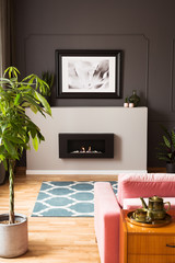 Framed photo above a minimalist, modern fireplace in a stylish living room interior with vibrant and wooden furniture. Real photo.