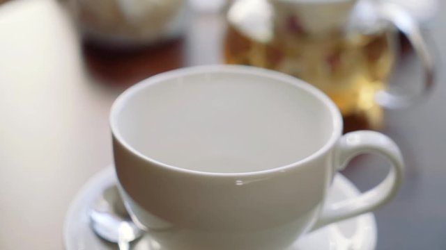 The hand of the girl puts sugar raffinate in a cup for tea.