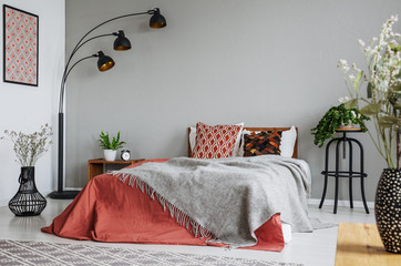 Patterned pillow and grey blanket on king size bed with dark orange duvet in luxury bedroom...