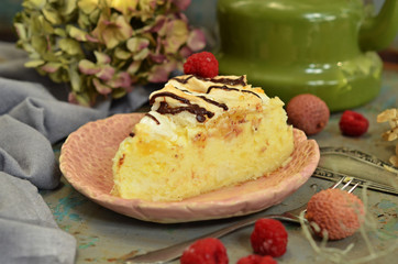 A piece of cheesecake with pineapple and raspberries on a rustic plate