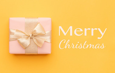 Fototapeta na wymiar Christmas background. Beautiful christmas gift isolated on bright yellow background. Pink xmas box. Gift wrapping concept.