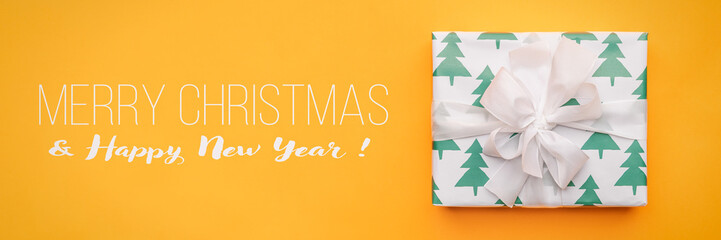 Christmas banner. Beautiful christmas gift isolated on bright yellow background. Turquoise colored wrapped xmas box. Gift wrapping concept.