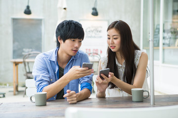 カフェでスマホを使う20代男女