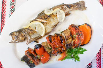 Grilled fish and grilled vegetables on a white plate.