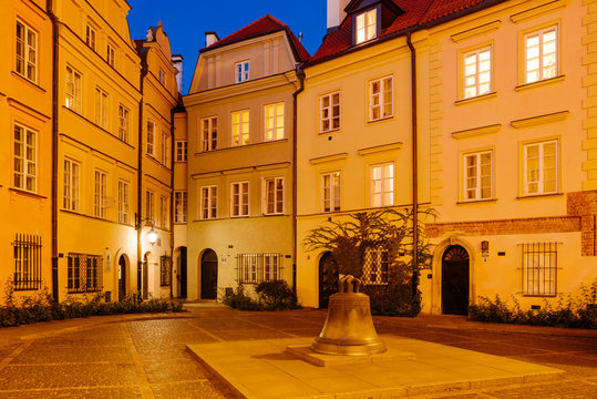 The wishing Bell and old townhouses in Kanonia Square in Warsaw at Night.