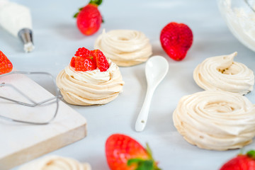 Strawberry pavlova cake nests, meringue decoration on a culinary table