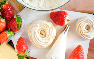 Strawberry pavlova cake nests, meringue decoration on a culinary table