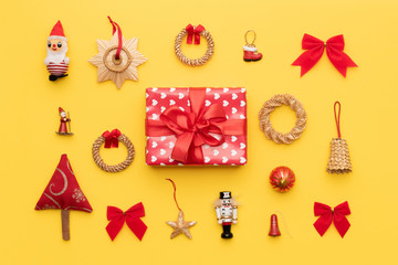 Red christmas gift and many retro christmas ornaments isolated on bright yellow background. Christmas composition.