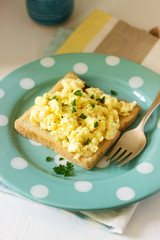 Simple classic breakfast of bread toast and scrambled eggs with parsley.