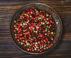 Peas of a red, green, white pepper in a copper saucer