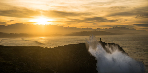 A MAN IN FRONT THE WAVES DURING THE SUNSET