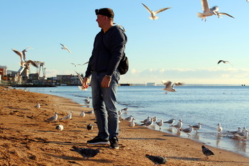 Man and seagulls on the sandy beach of the sea coast