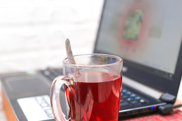 Work at home, distant work, freelancing. Laptop and cup of tea closeup.