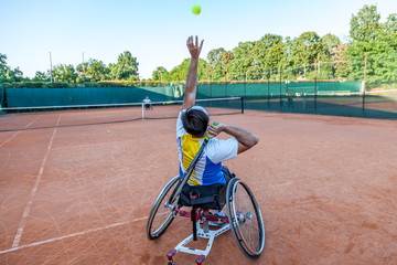 disabled tennis player hits the ball for service
