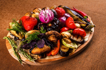 Various grilled vegetables on a round wooden Board. Tomatoes, zucchini, onions, eggplant, mushrooms, paprika