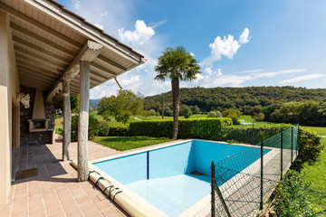 Villa with pool and surrounded by green lawn on a summer day