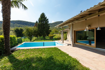 Villa with pool and surrounded by green lawn on a summer day