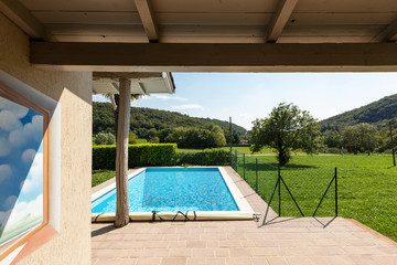 Fototapeta na wymiar Villa with pool and surrounded by green lawn on a summer day