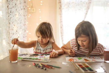 children girlfriends paint at table in real room